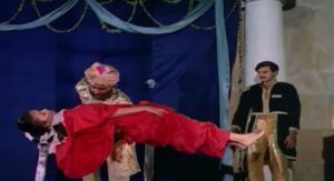A magician performs a levitation trick with a woman in a red costume floating mid-air on stage, as an assistant watches in the background, from the film Pushpak (1987).